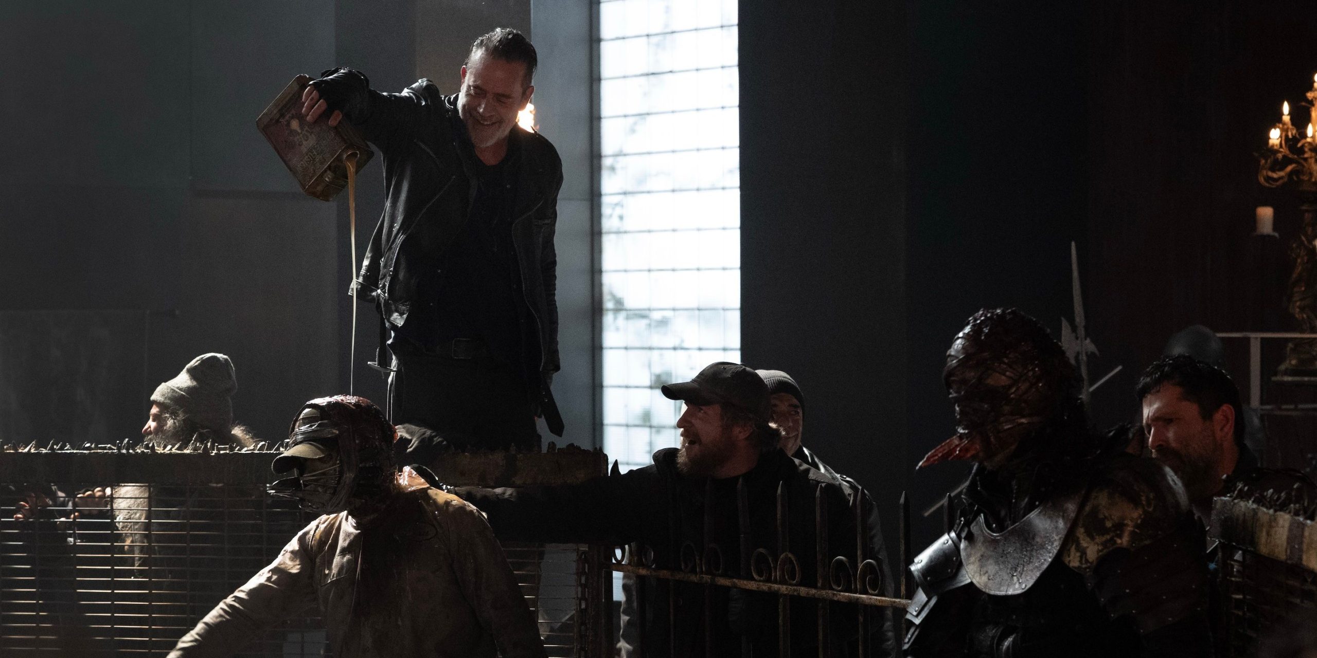 Negan verse de l'huile sur un rôdeur dans une fosse de combat dans The Walking Dead : Dead City.