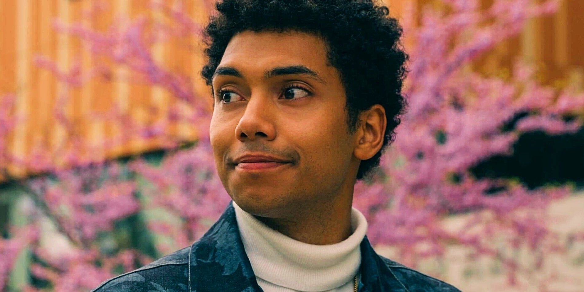 Chance Perdomo dans le rôle d'André souriant dans la saison 1 de Gen V avec un cerisier en fleurs derrière lui