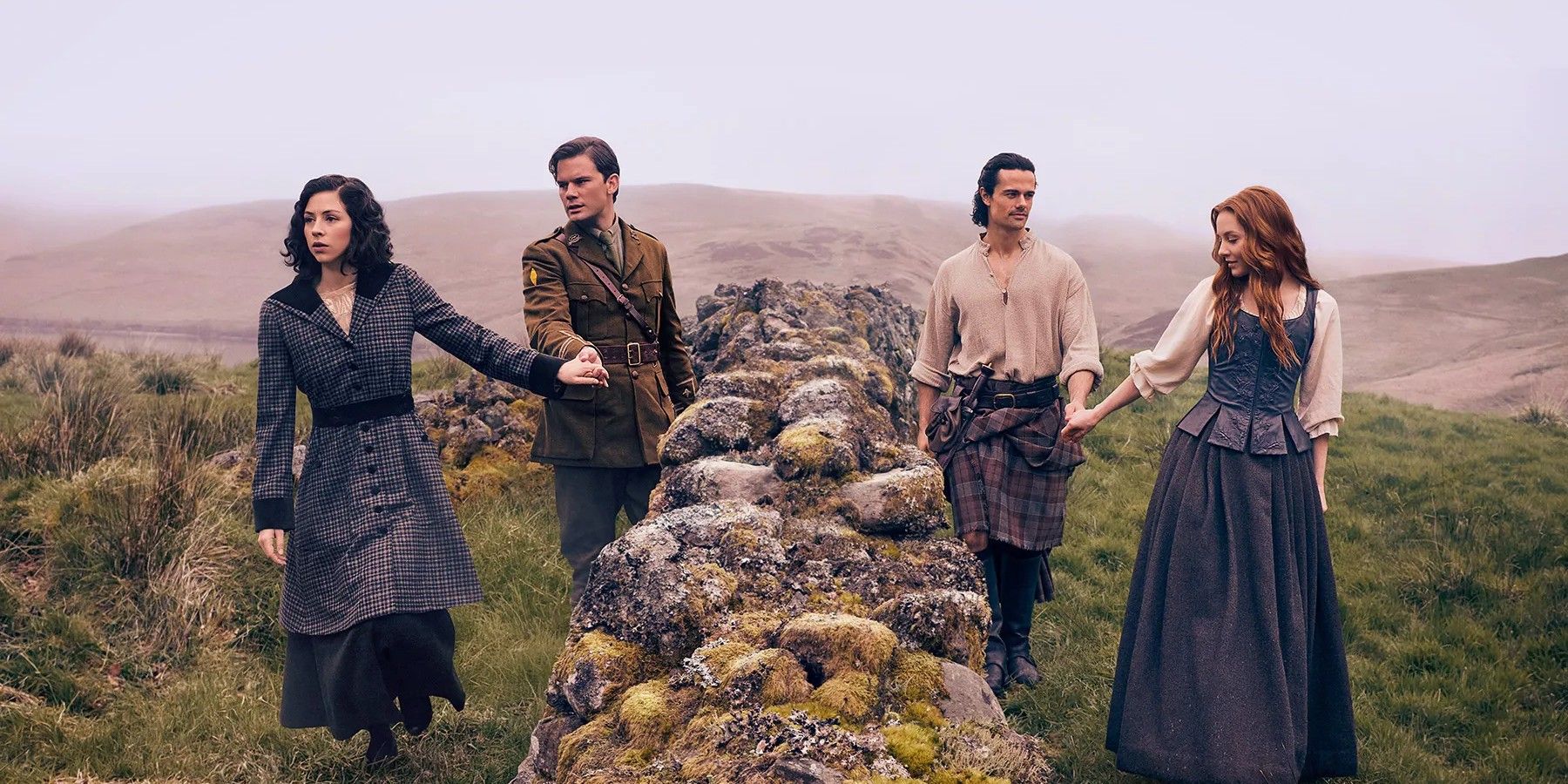 Les acteurs d'Outlander: Blood of My Blood marchent près d'un mur de pierre.