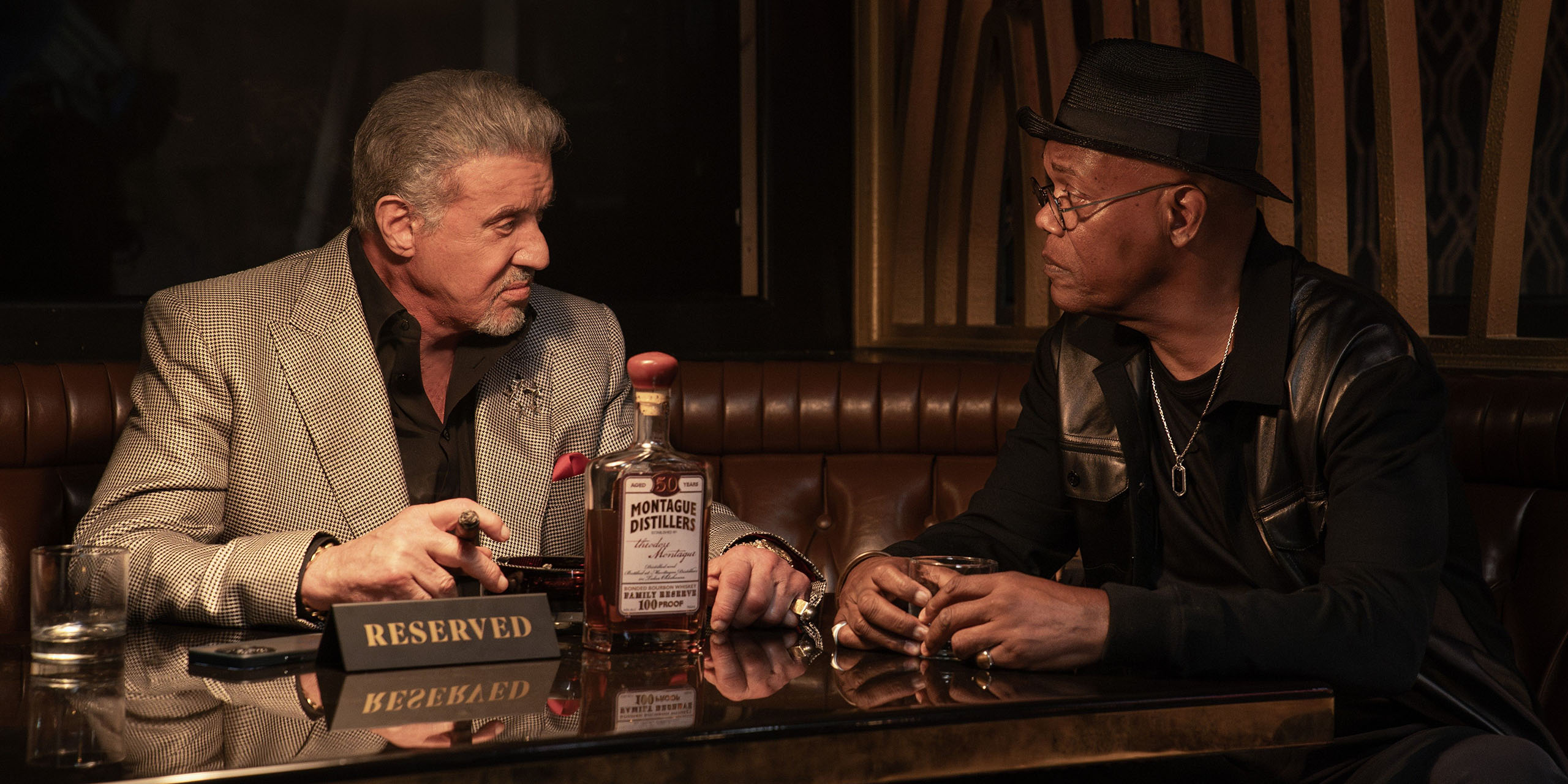Dwight Manfredi (Sylvester Stallone) et Russell Lee Washington Jr. (Samuel L. Jackson) assis à un stand dans la saison 3 de Tulsa King