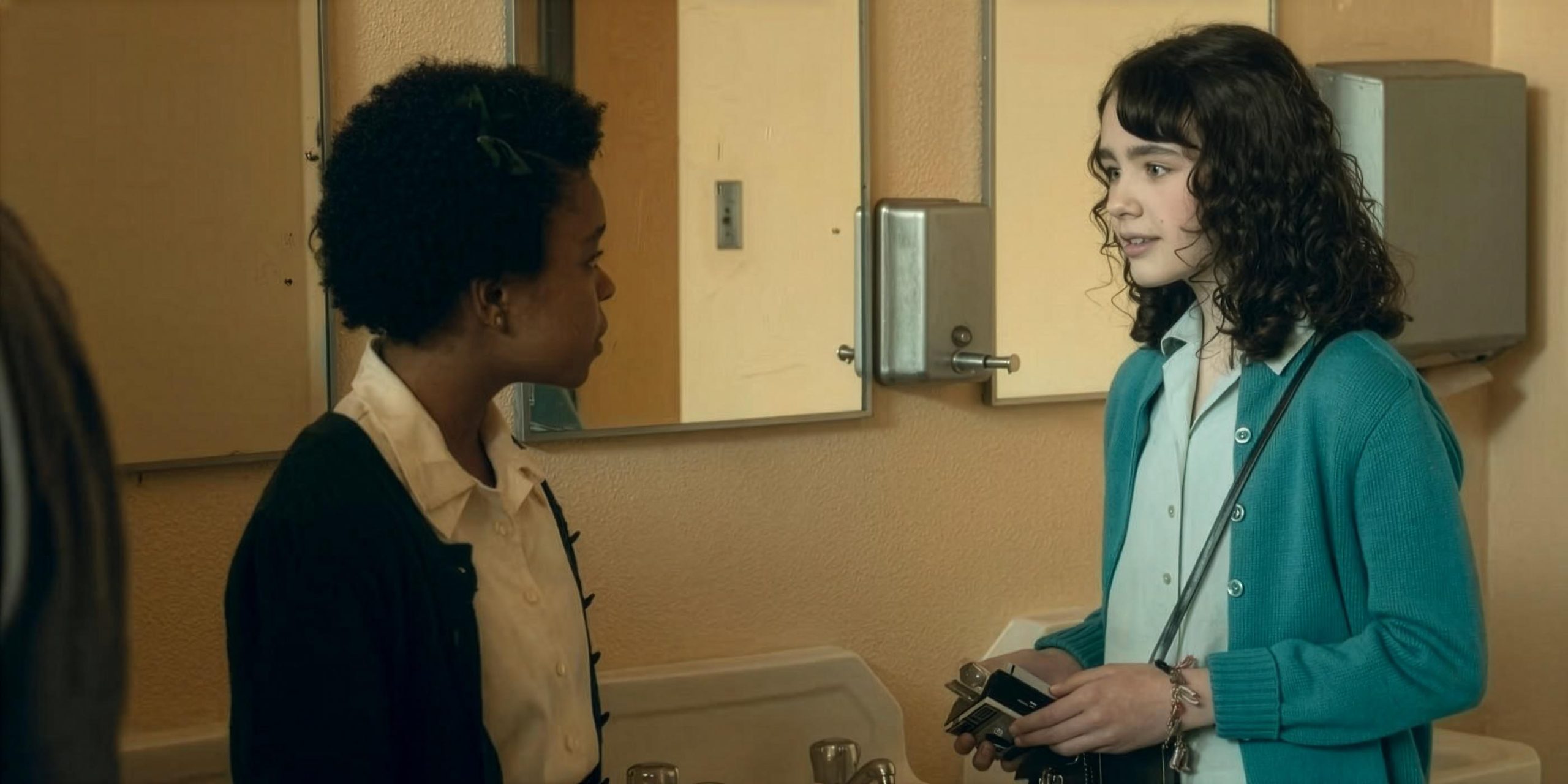 Ronnie (Amanda Christine) et Lilly (Clara Stack) discutent dans la les toilettes du lycée dans Ça : Bienvenue à Derry.