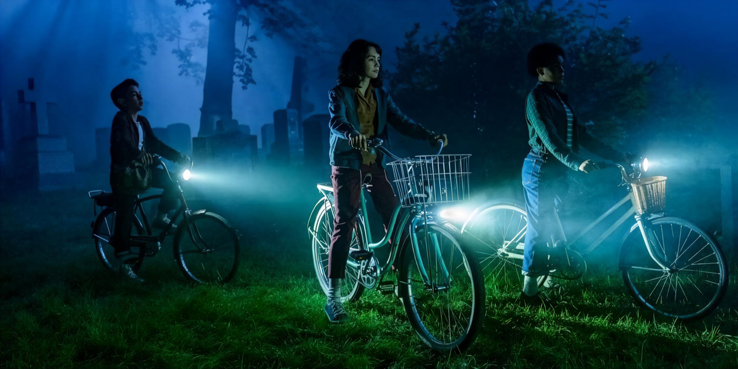 Rich (Arian S. Cartaya), Lilly (Clara Stack) et Ronnie (Amanda Christine) parcourent un cimetière à vélo la nuit dans Ça : Bienvenue à Derry.