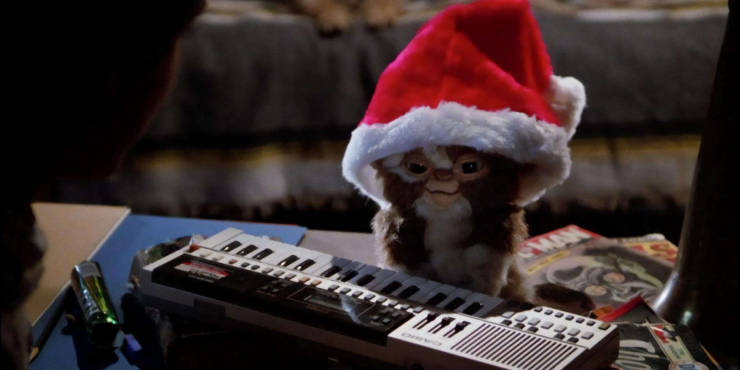 Gizmo le mogwai portant un bonnet de Noël et jouant du synthé dans Gremlins.