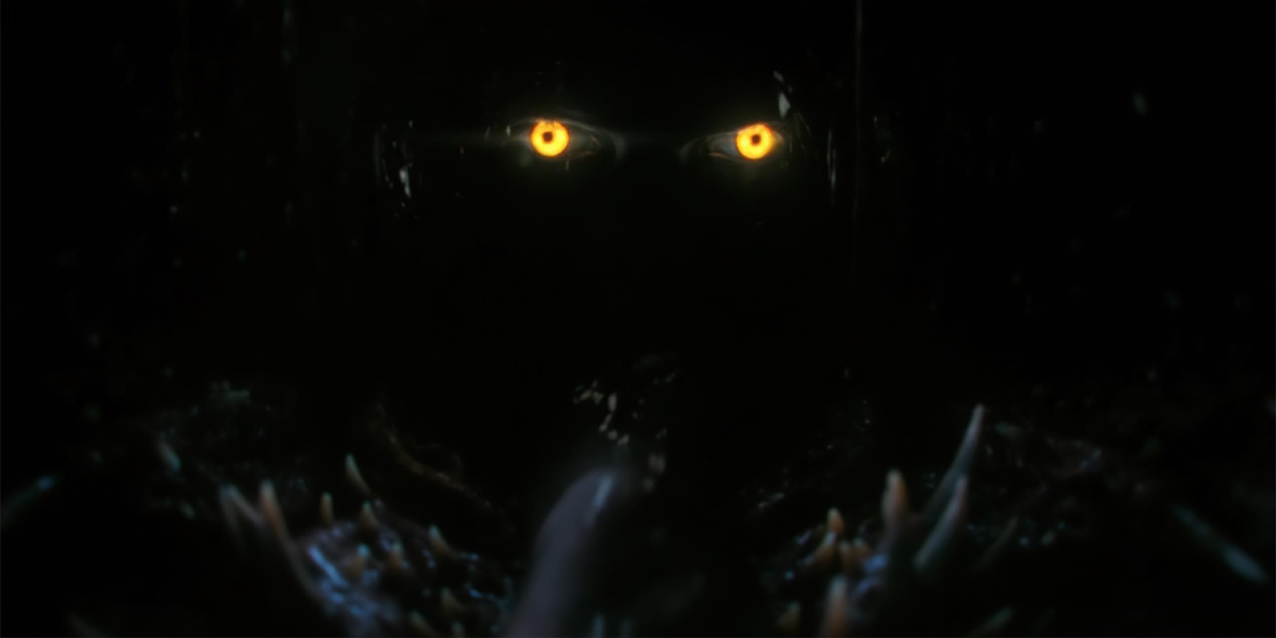 Les yeux jaunes de Pennywise à l'intérieur d'une bouche sombre dans Ça : Bienvenue à Derry.