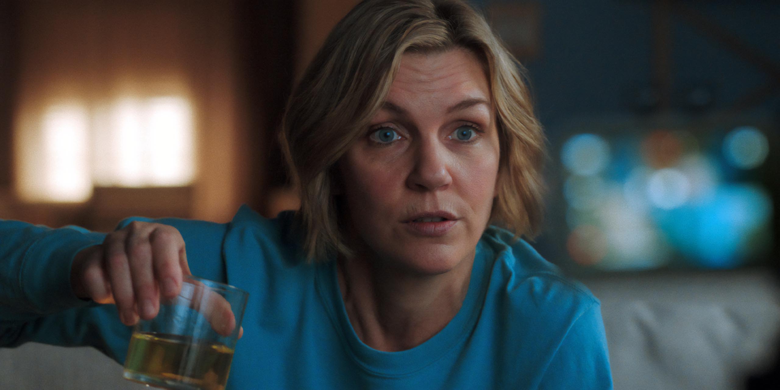 Carol (Rhea Seehorn) tenant un verre de l'étrange liquide jaune dans l'épisode 5 de Pluribus.