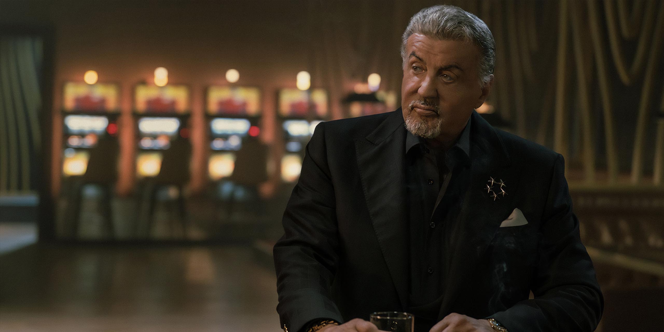 Sylvester Stallone dans le rôle de Dwight Manfredi buvant un whisky dans Tulsa King, saison 3, épisode 10.