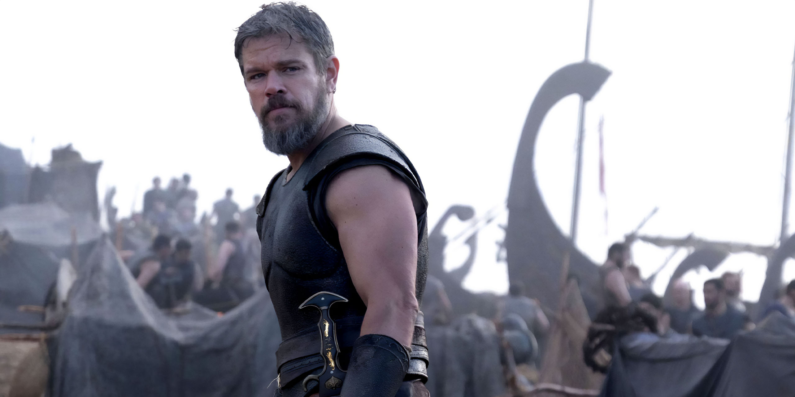 Matt Damon dans le rôle d'Ulysse, regardant vers la gauche, avec un navire et son équipage derrière lui, dans L'Odyssée.
