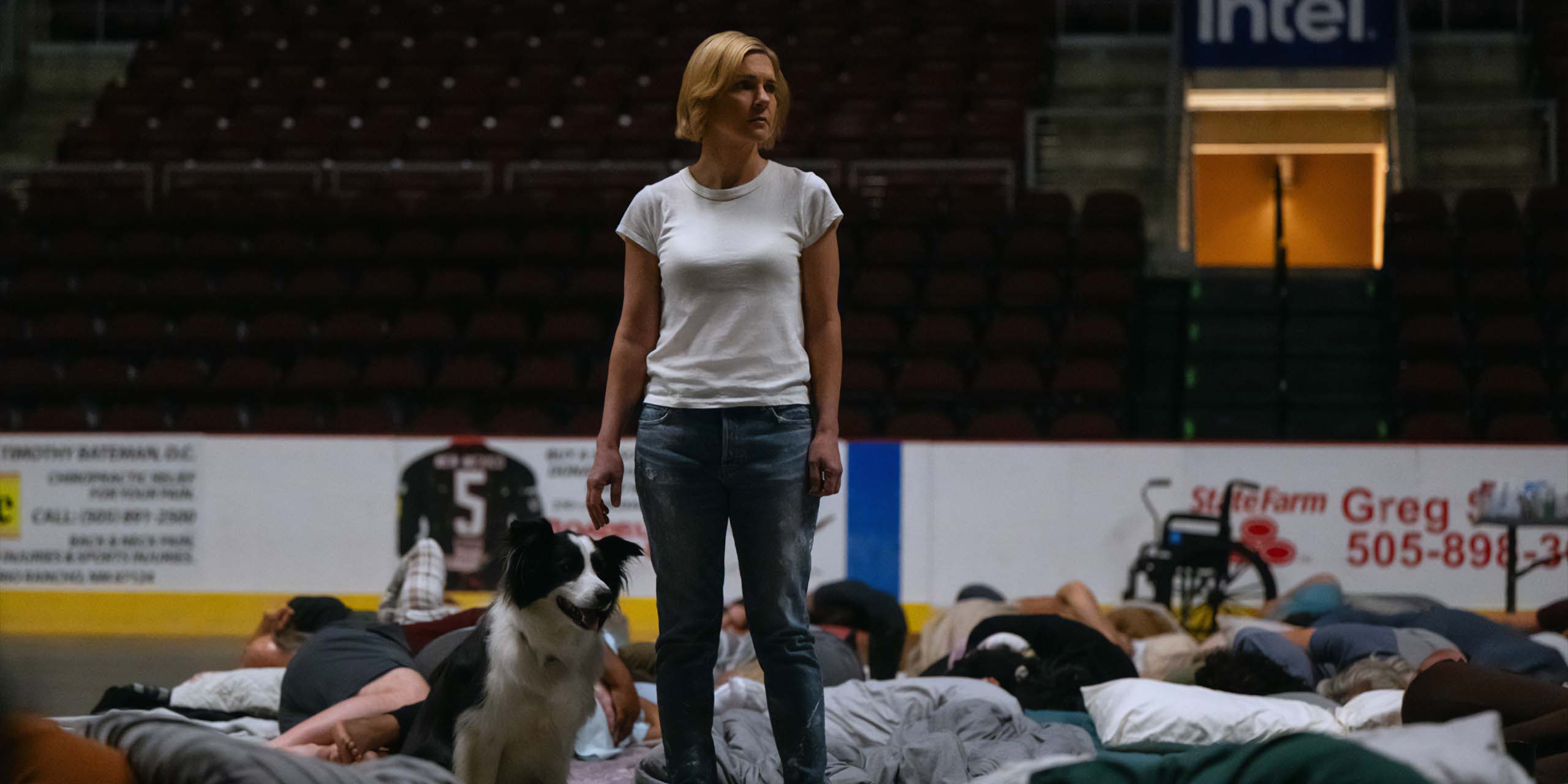 Carol (Rhea Seehorn) au milieu du dortoir des Autres dans un gymnase, dans Pluribus.