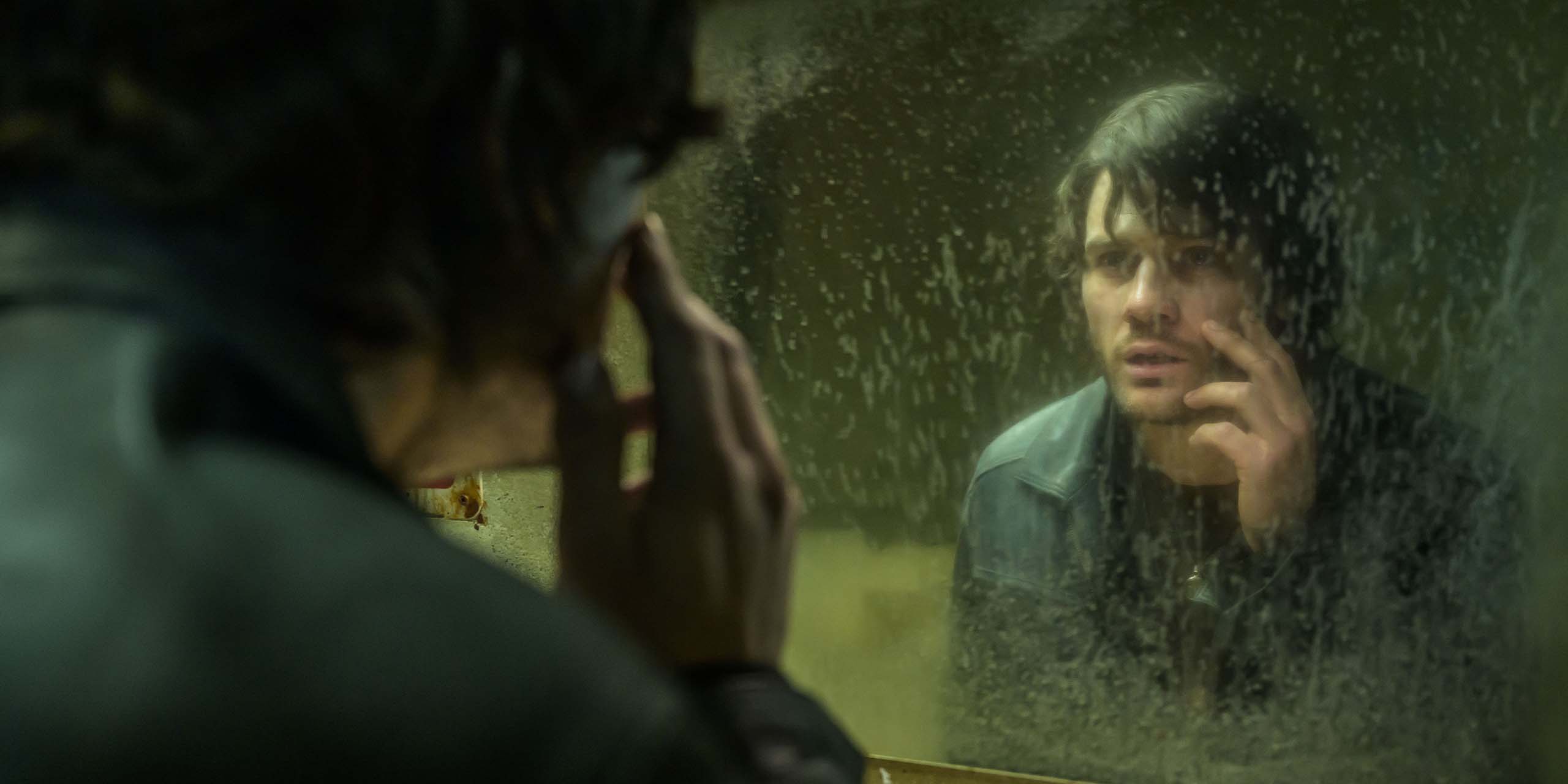 Jeremy Irvine, dans le rôle de James Sunderland, l'air soucieux devant un miroir sale dans Retour à Silent Hill.