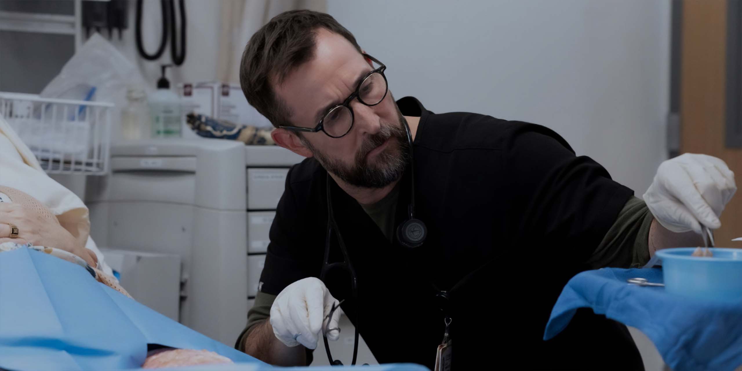 Dr. Michael "Robby" Robinavitch (Noah Wyle) auscultant un patient dans The Pitt, saison 2, épisode 3