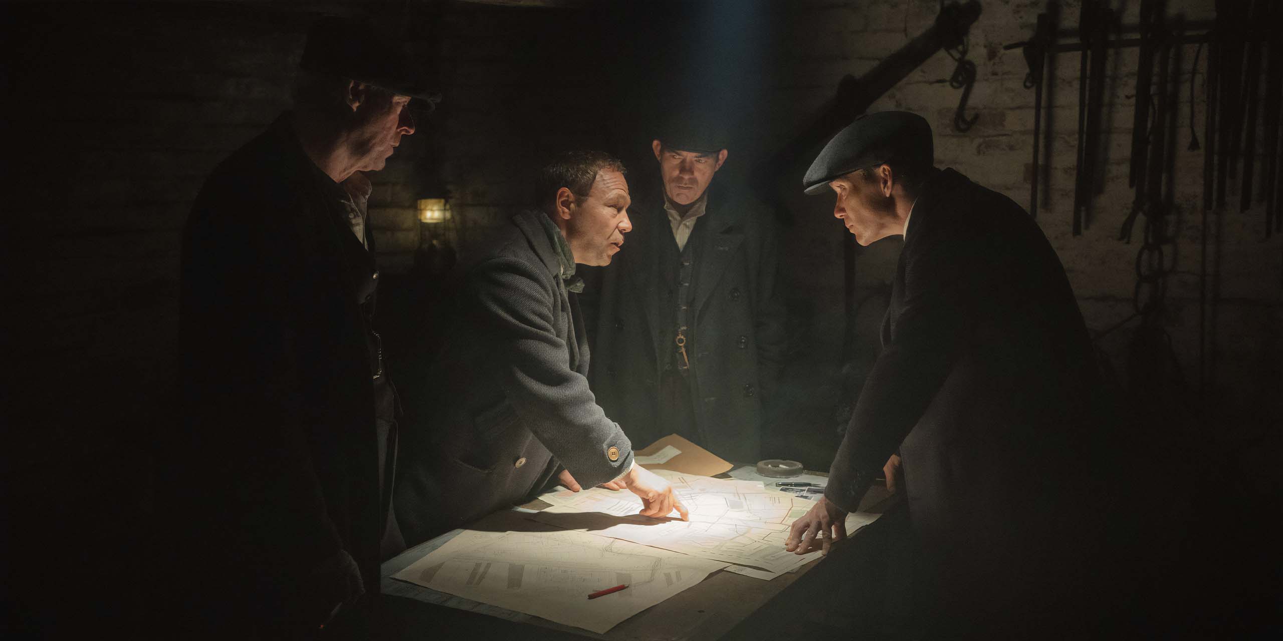 Quatre personnages qui consultent des papiers dans Peaky Blinders: The Immortal Man.