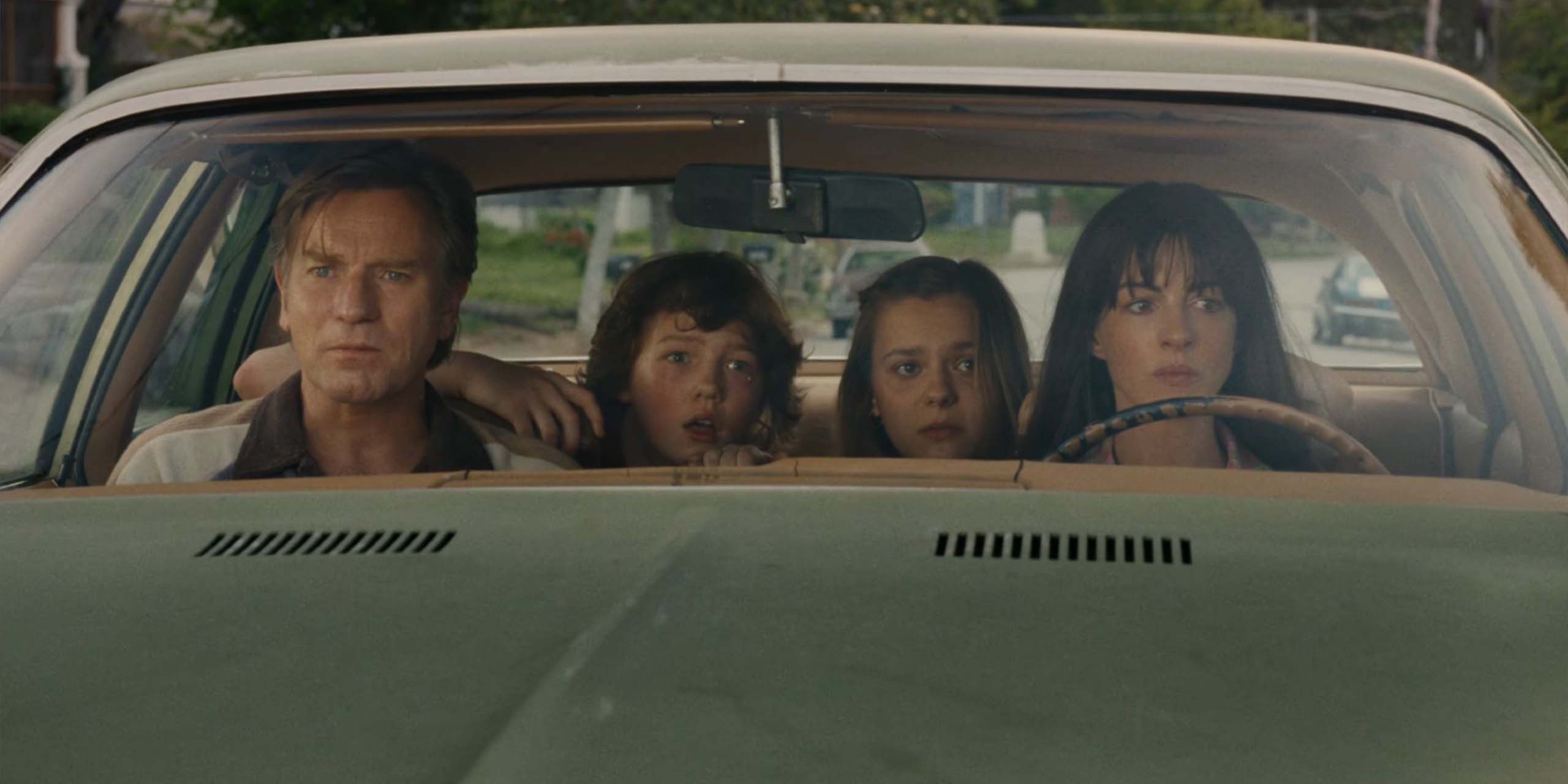 Anne Hathaway et Ewan McGregor sont assis dans une voiture avec leurs enfants dans La Fin d'Oak Street.