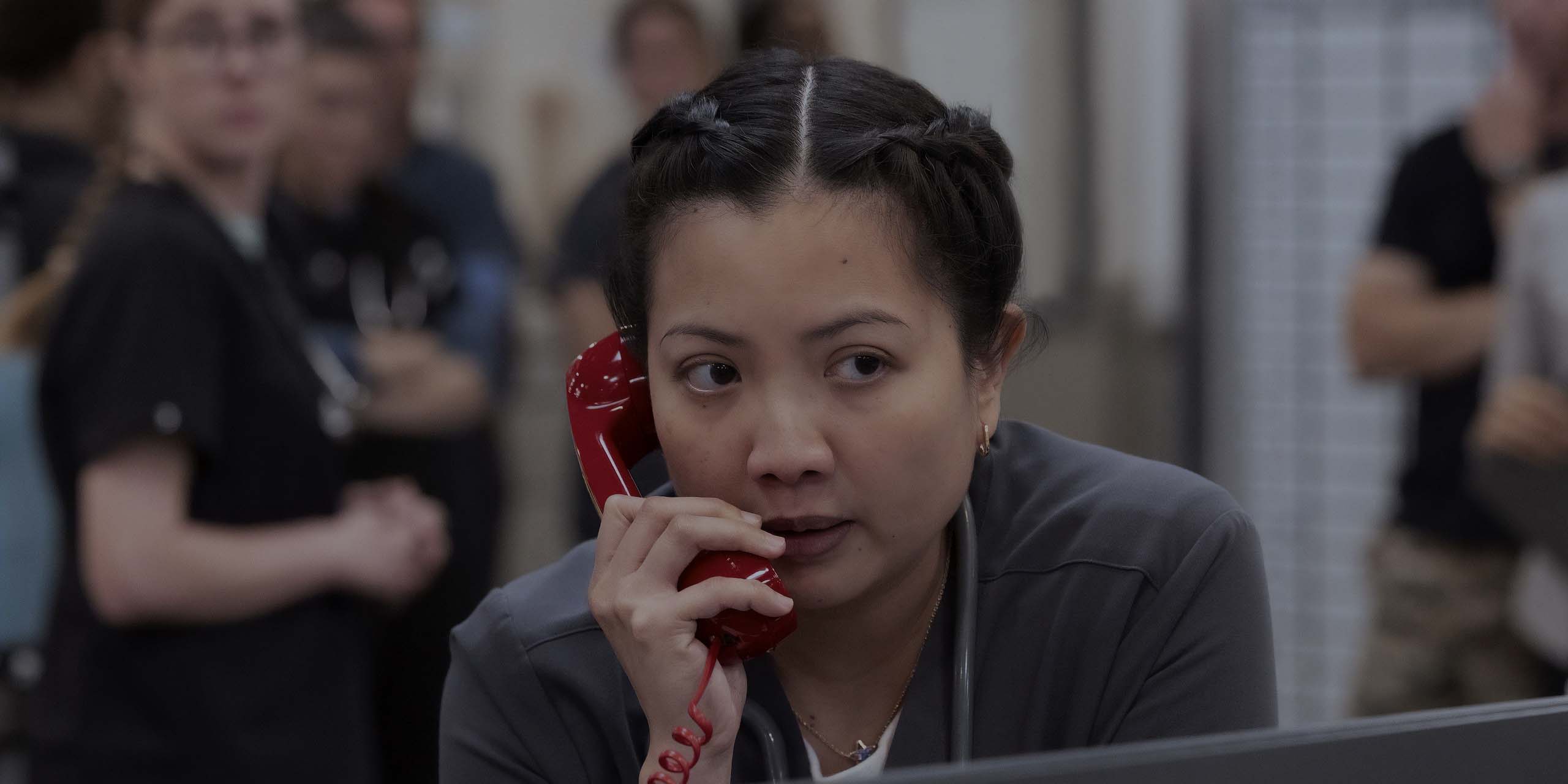 Princesse (Kristin Villanueva) tenant un téléphone rouge dans la saison 2 de The Pitt