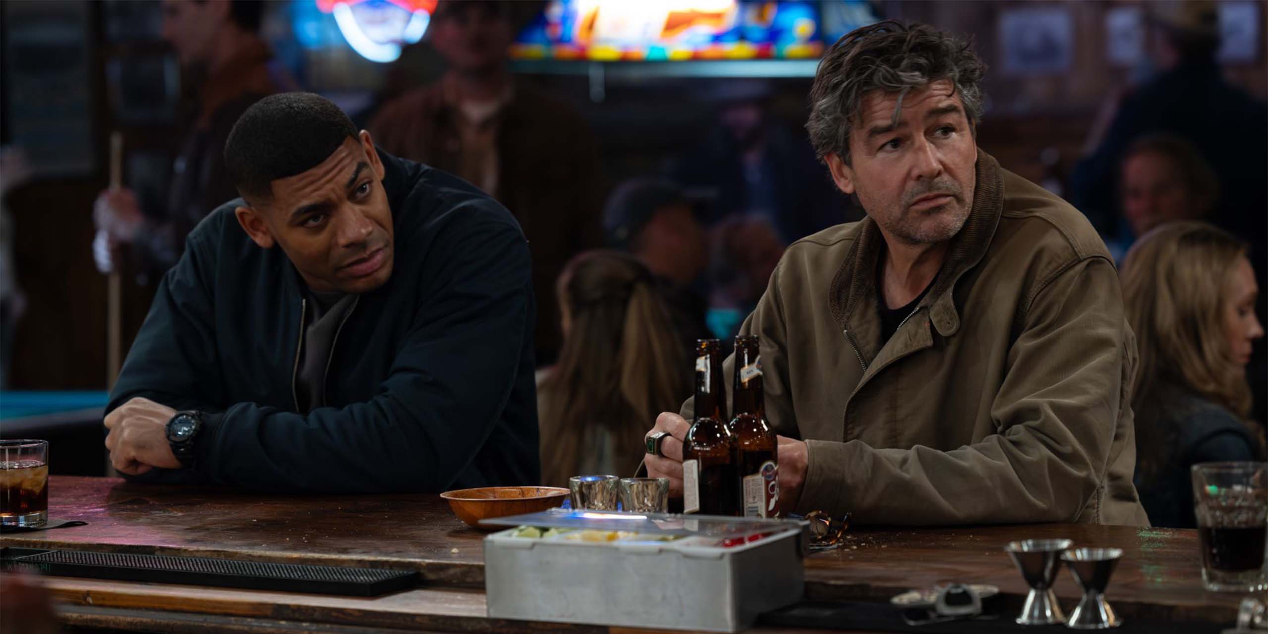 John Stewart (Aaron Pierre) et Hal Jordan (Kyle Chandler) dans un bar dans la série Lanterns.