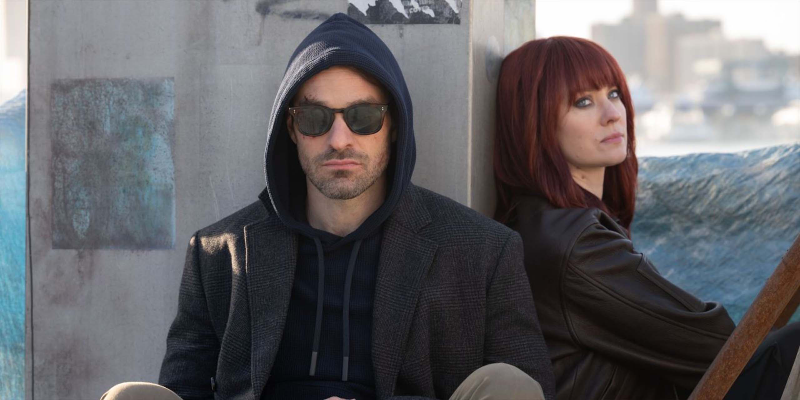 Matt Murdock (Charlie Cox) portant des lunettes de soleil et sa capuche relevée, et Karen Page (Deborah Ann Woll), aux cheveux roux, sur un toit dans Daredevil : Born Again Saison 2