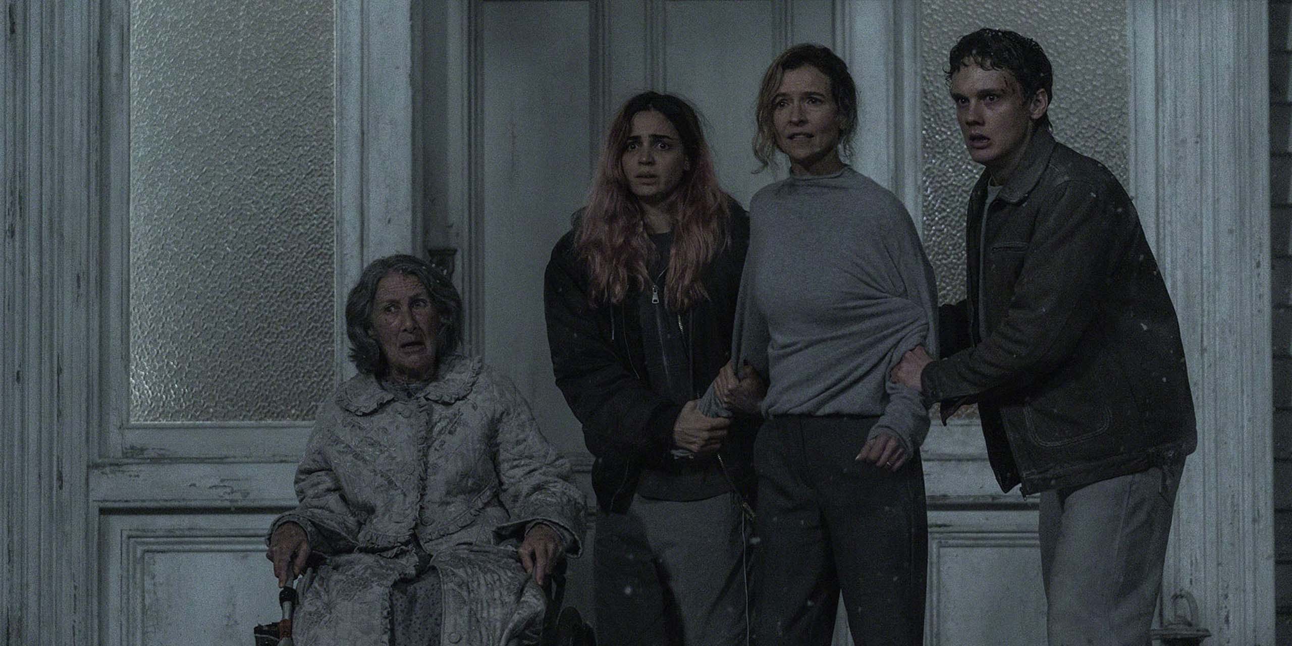 Quatre personnes se blottissent les unes contre les autres, terrifiées, sur un porche à Evil Dead Burn.