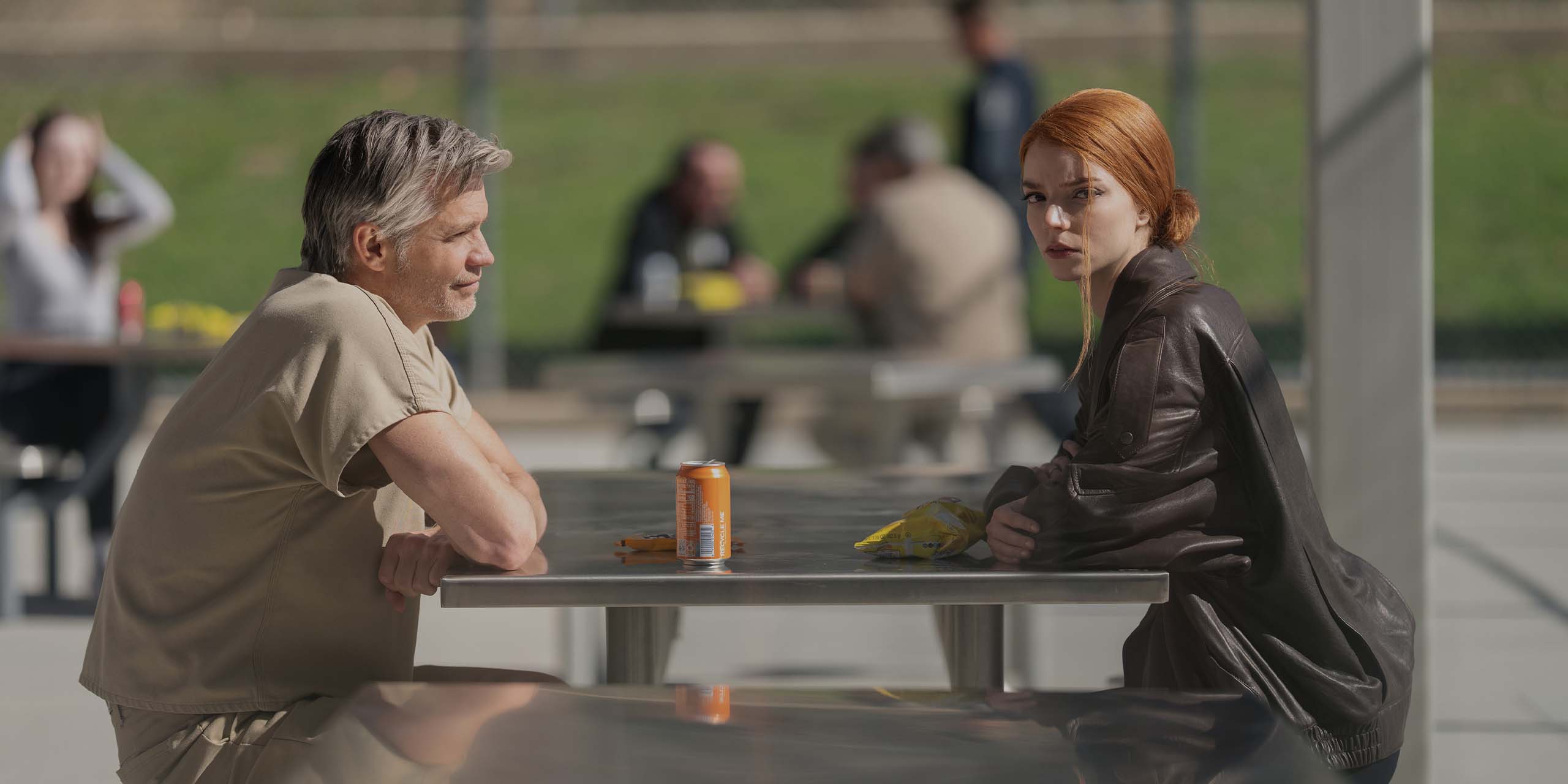 John Armstrong (Timothy Olyphant) et Lucky (Anya Taylor-Joy) discutent à une table dans la cour d'une prison.