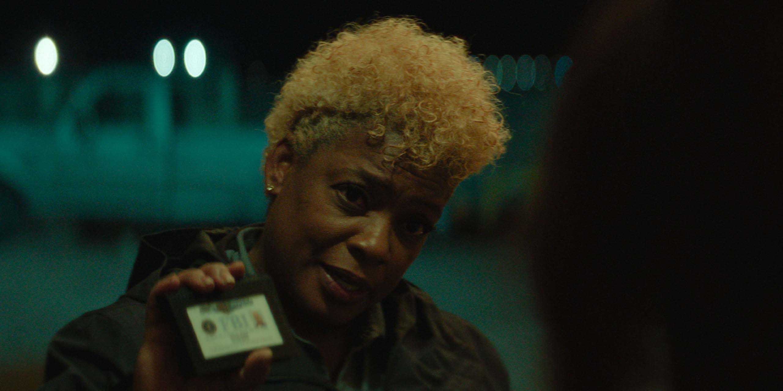Aunjanue Ellis-Taylor montrant sa carte d'agent de police dans Lucky.