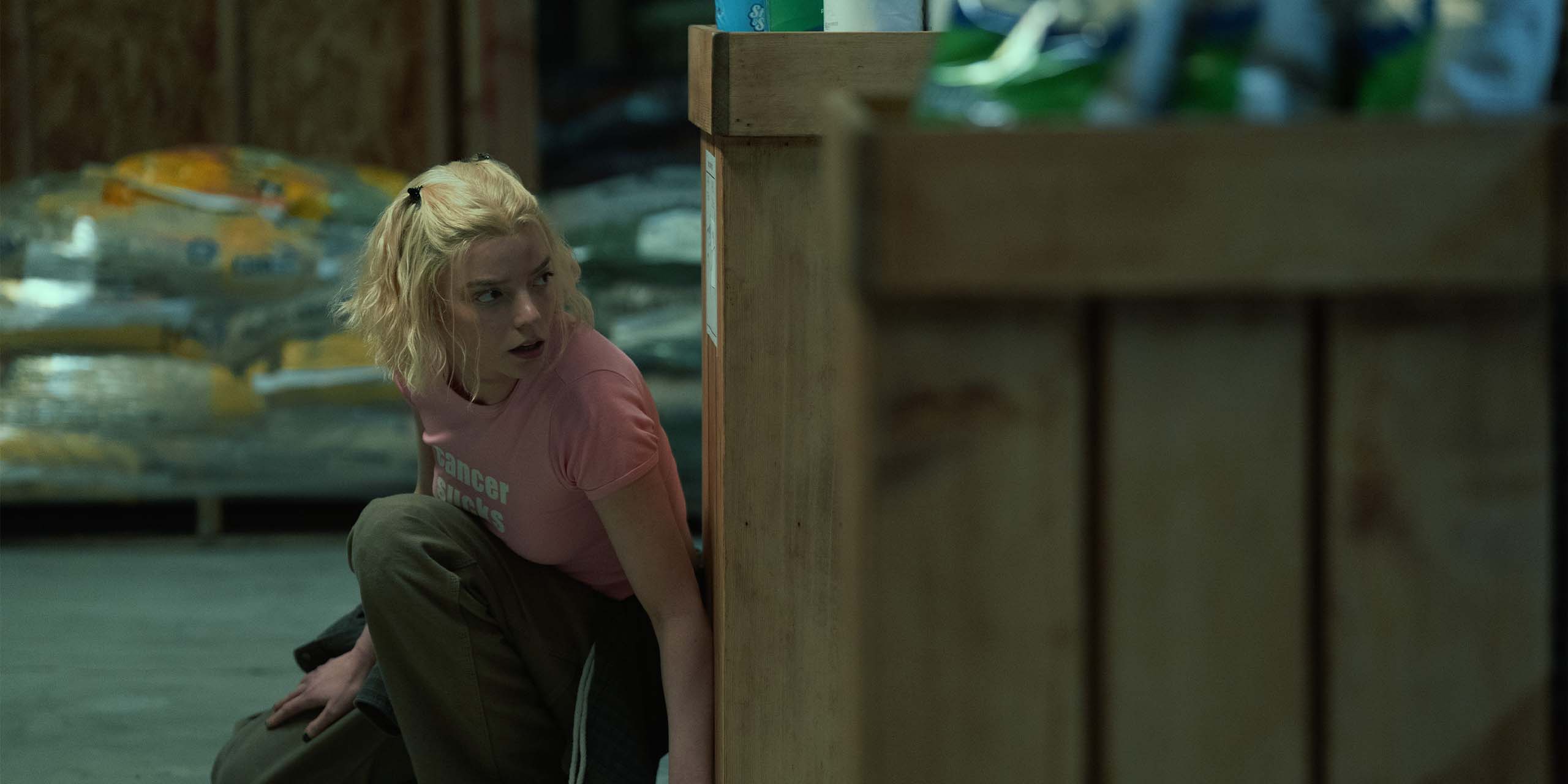 Lucky (Anya Taylor-Jones) se cache derrière une caisse en bois dans la série Lucky.