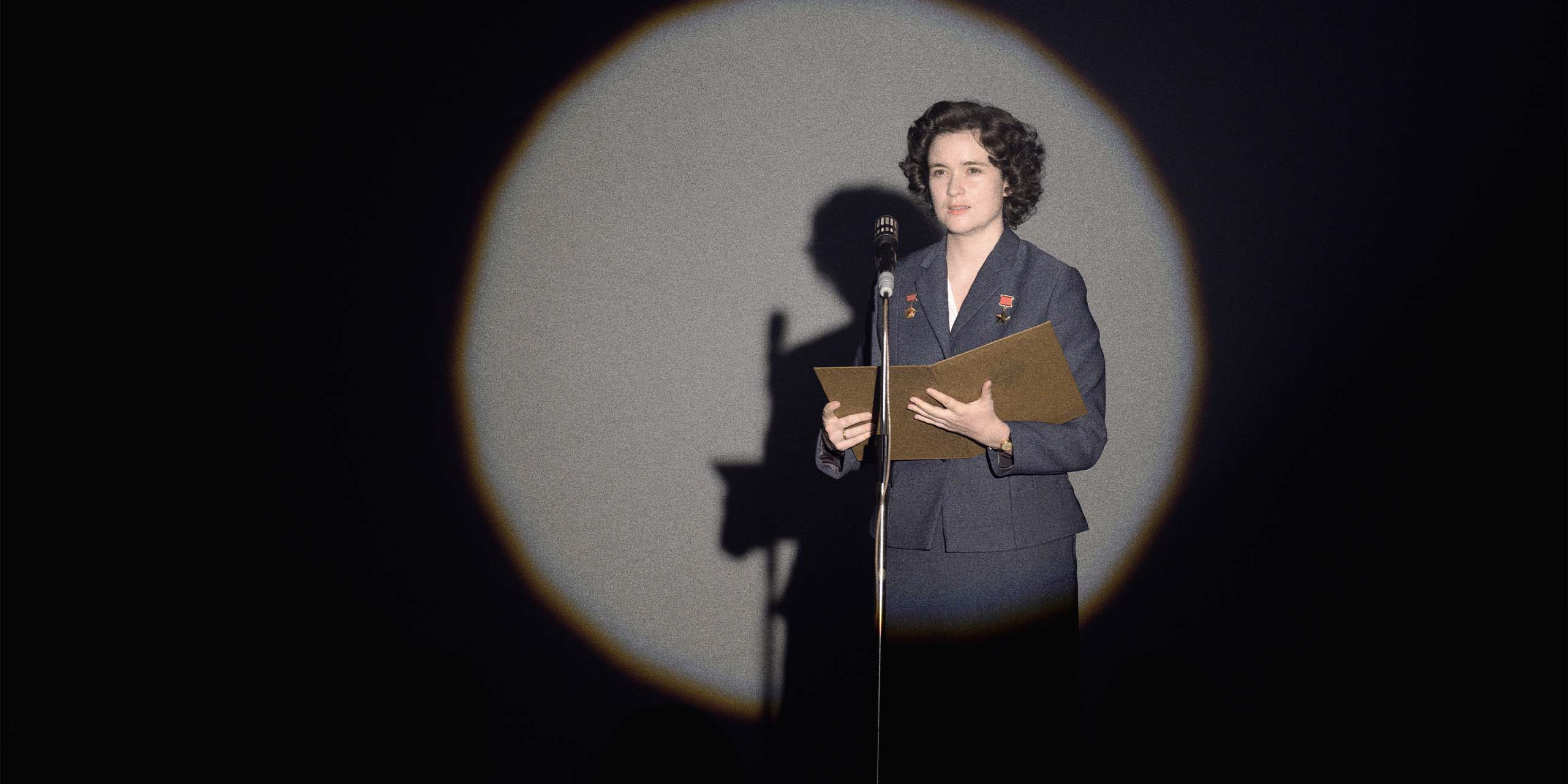 Anastasia Belikova (Alice Englert) sur scène au micro sous le projecteur dans Star City.