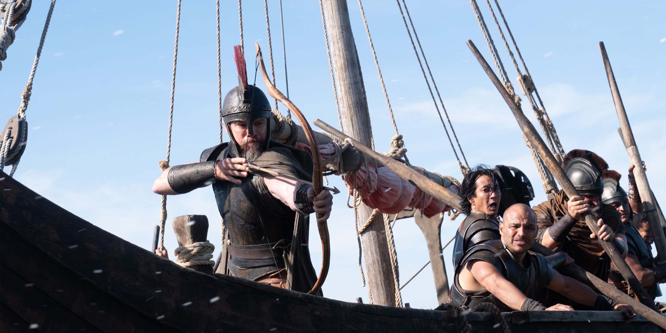 Sur son navire, Ulysse (Matt Damon) s'apprête à envoyer une flèche avec son arc dans L'Odyssée.