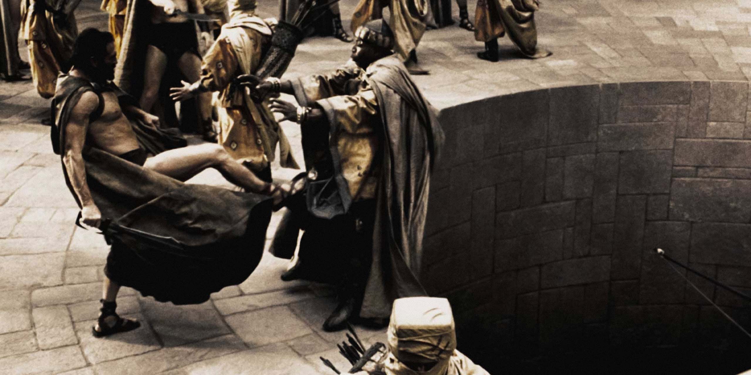 Un guerrier spartiate frappe un dignitaire perse près d’un vaste puits dans une scène de « 300 ».