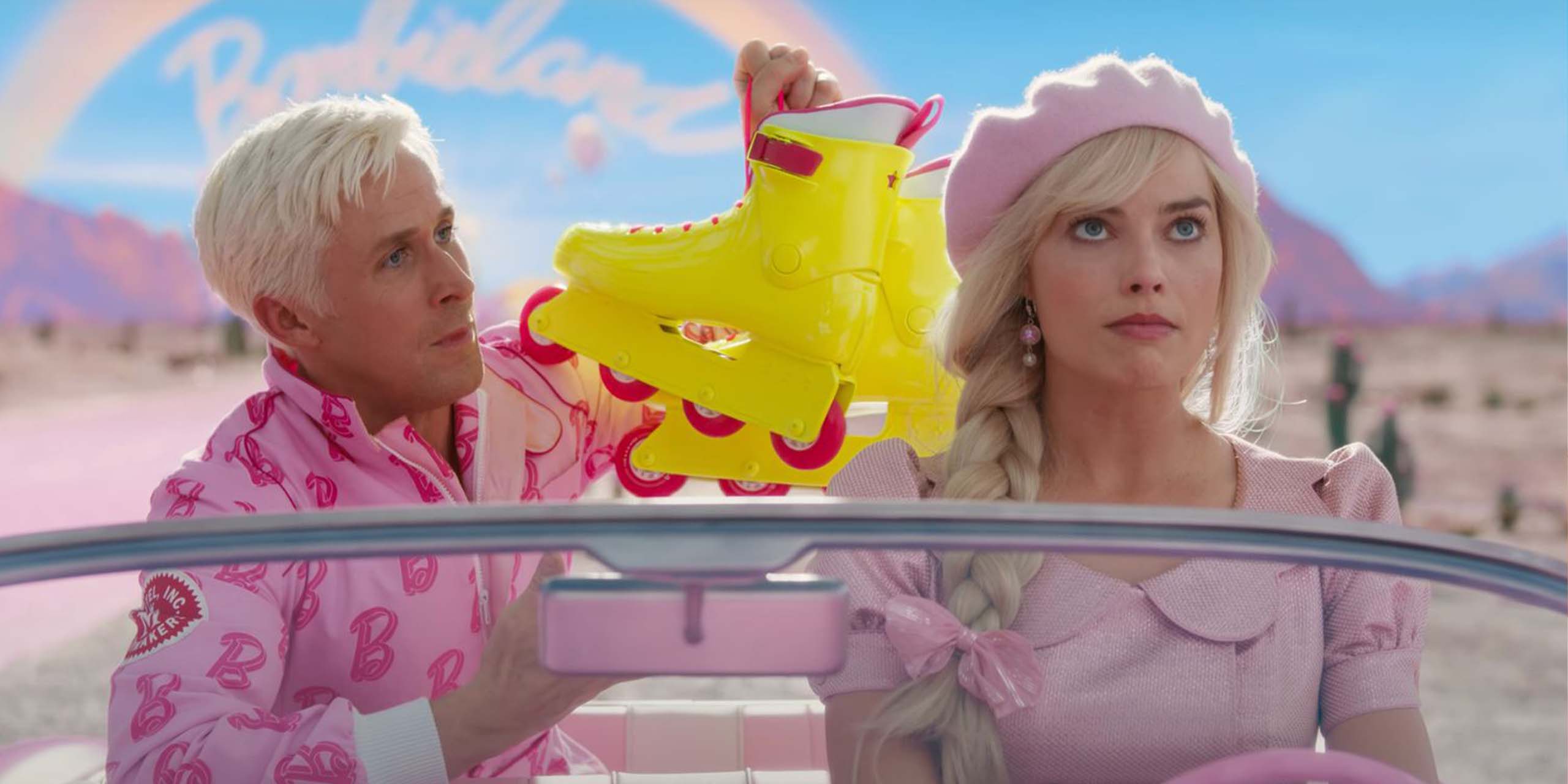 Ryan Gosling (Ken) tend des patins à roulettes à Margot Robbie (Barbie) cpendant qu'elle conduit sa voiture.