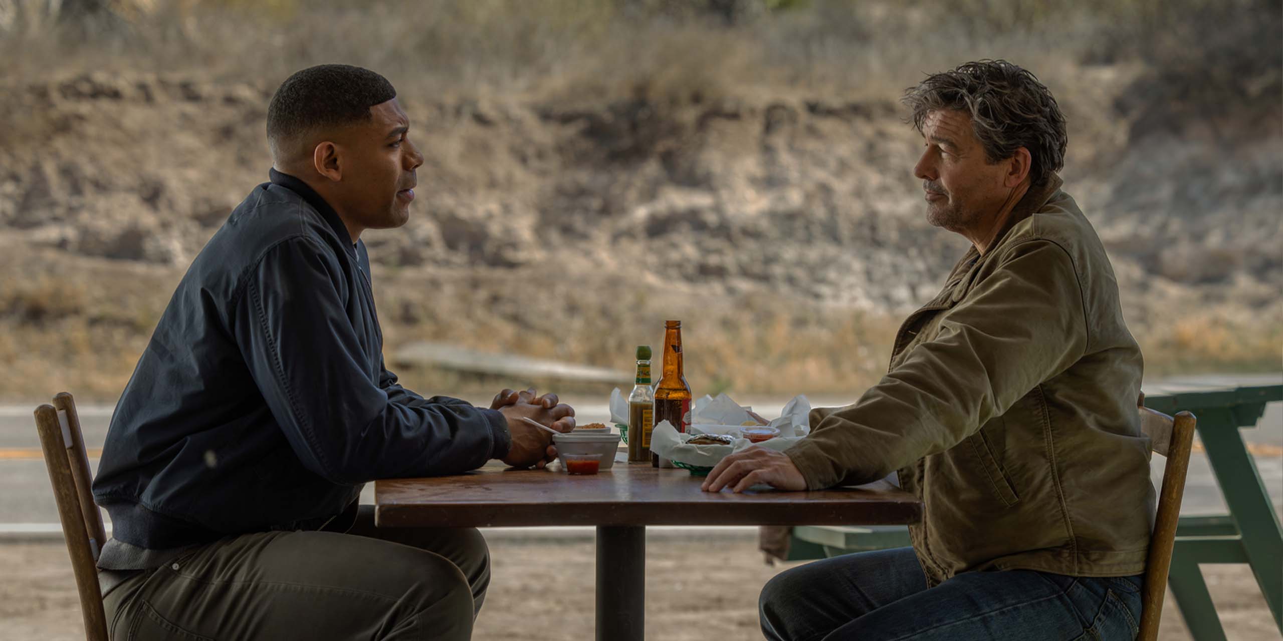John Stewart (Aaron Pierre) face à Hal Jordan (Kyle Chandler) à une table de restaurant dans Lanterns.
