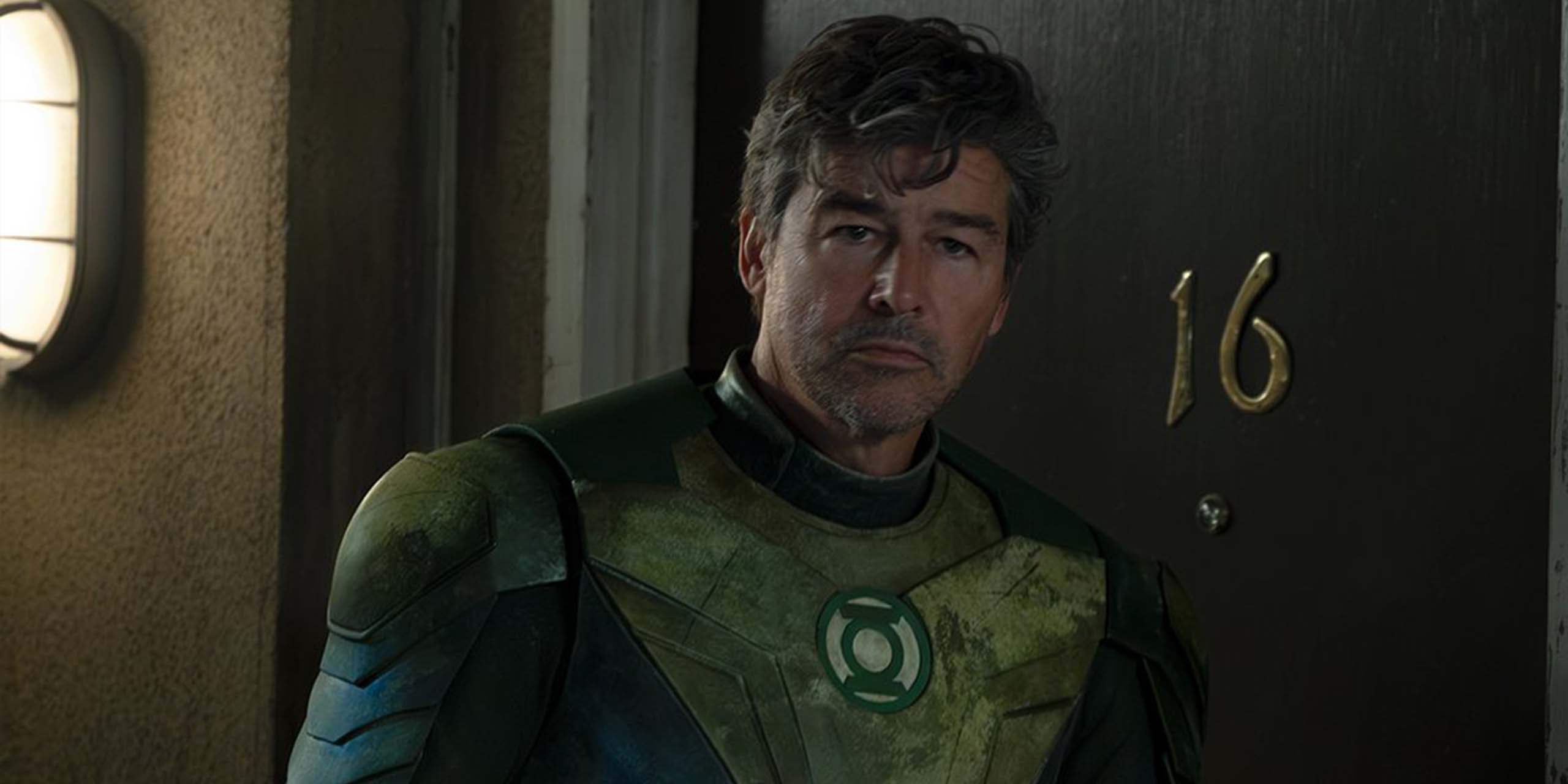Hal Jordan (Kyle Chandler) en tenue de Green Lantern sortant d'une chambre d'hôtel dans Lanterns.