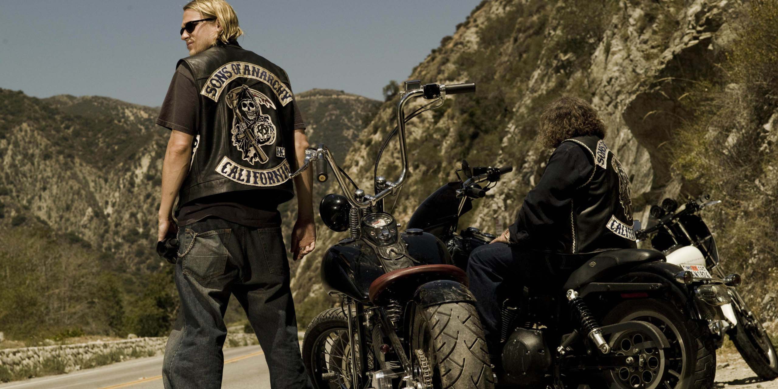 Jax Teller (Charlie Hunnam) debout près de sa moto dans Sons of Anarchy.