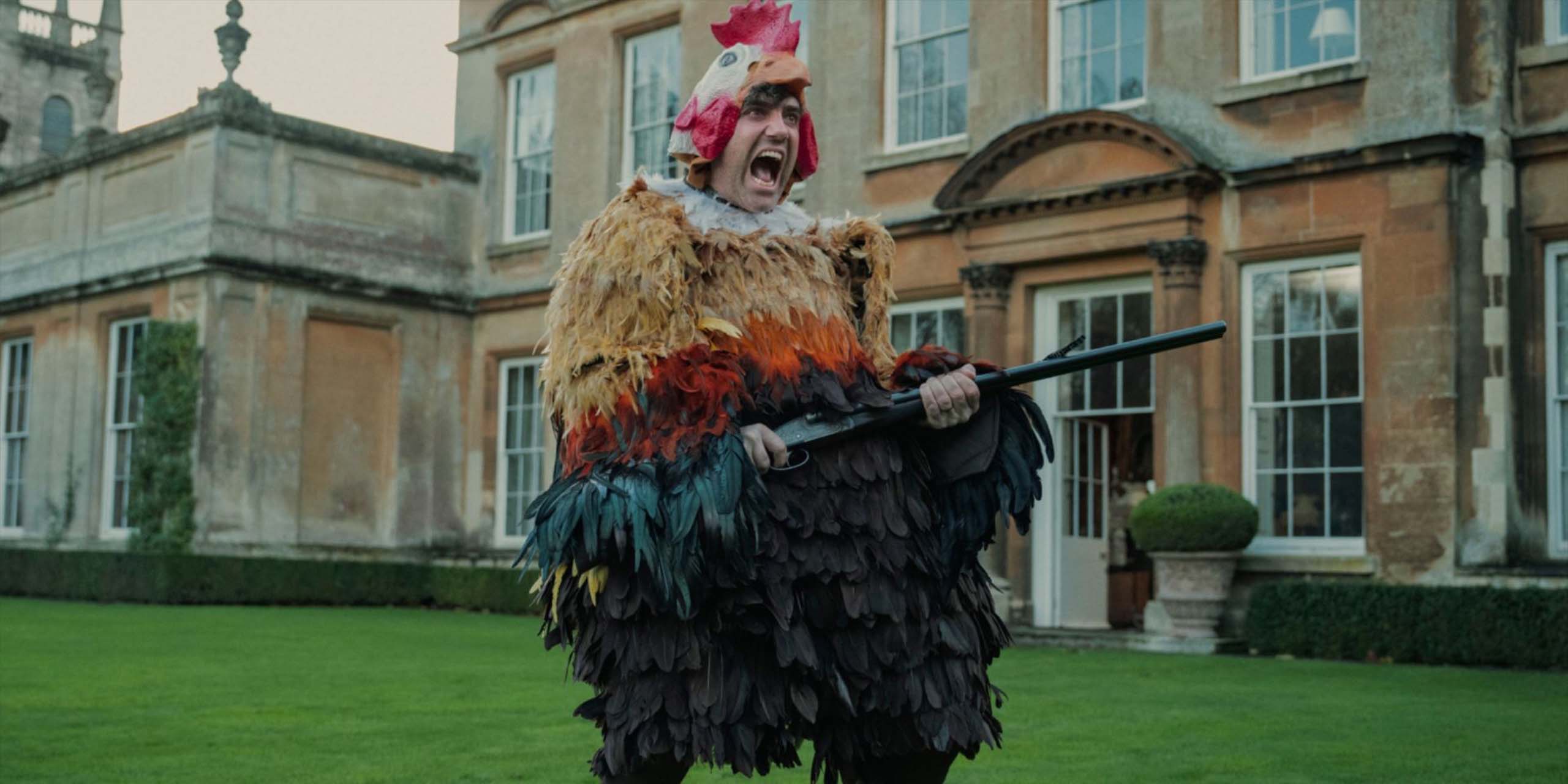 Daniel Ings dans le rôle de Freddy Horniman déguisé en poulet et pointant une arme à feu pour la série The Gentlemen de Netflix
