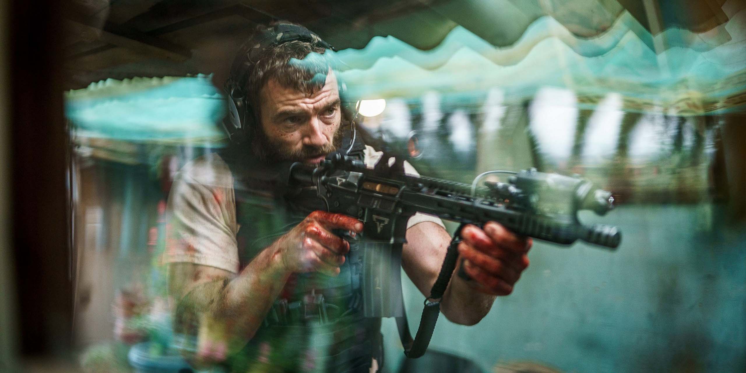Un homme aux mains ensanglantées vise avec un fusil d’assaut dans une scène de « The Last Photograph ».