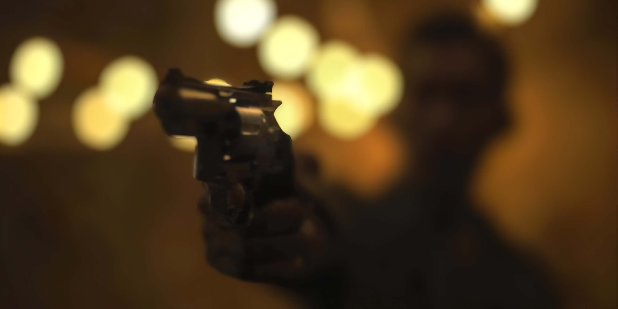 Un revolver pointé vers l’objectif dans une scène nocturne de « The Last Photograph ».
