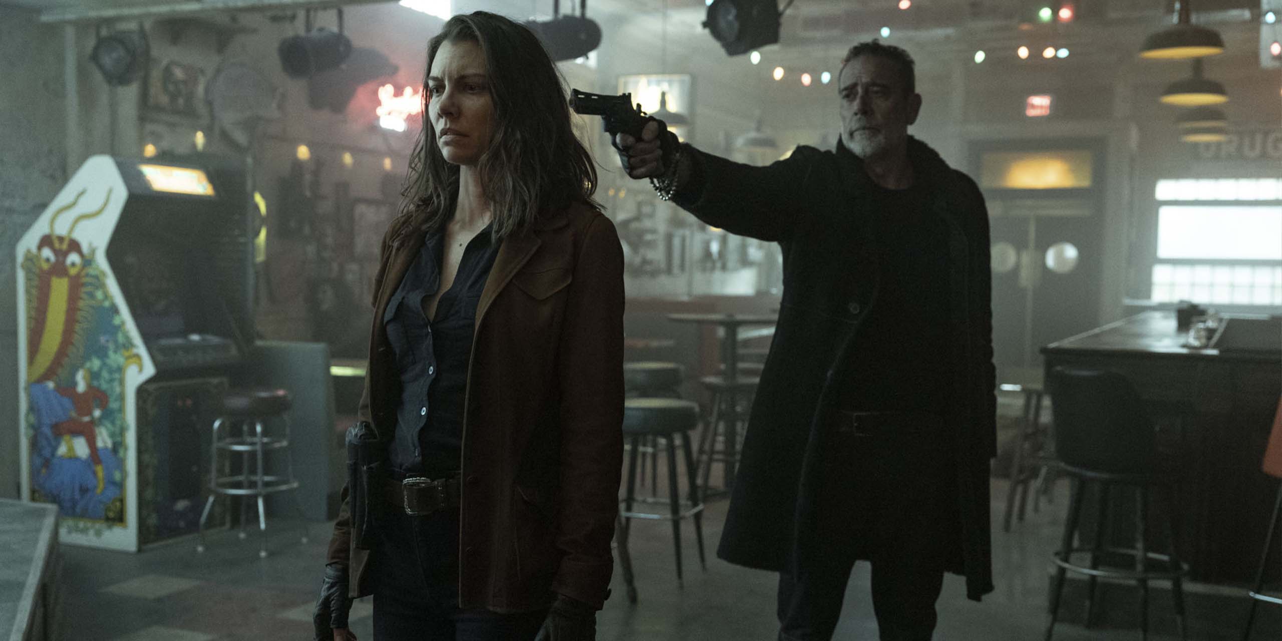 Negan (Jeffrey Dean Morgan) pointe son arme vers Maggie (Lauren Cohan) qui lui tourne le dos dans un bar de The Walking Dead : Dead City