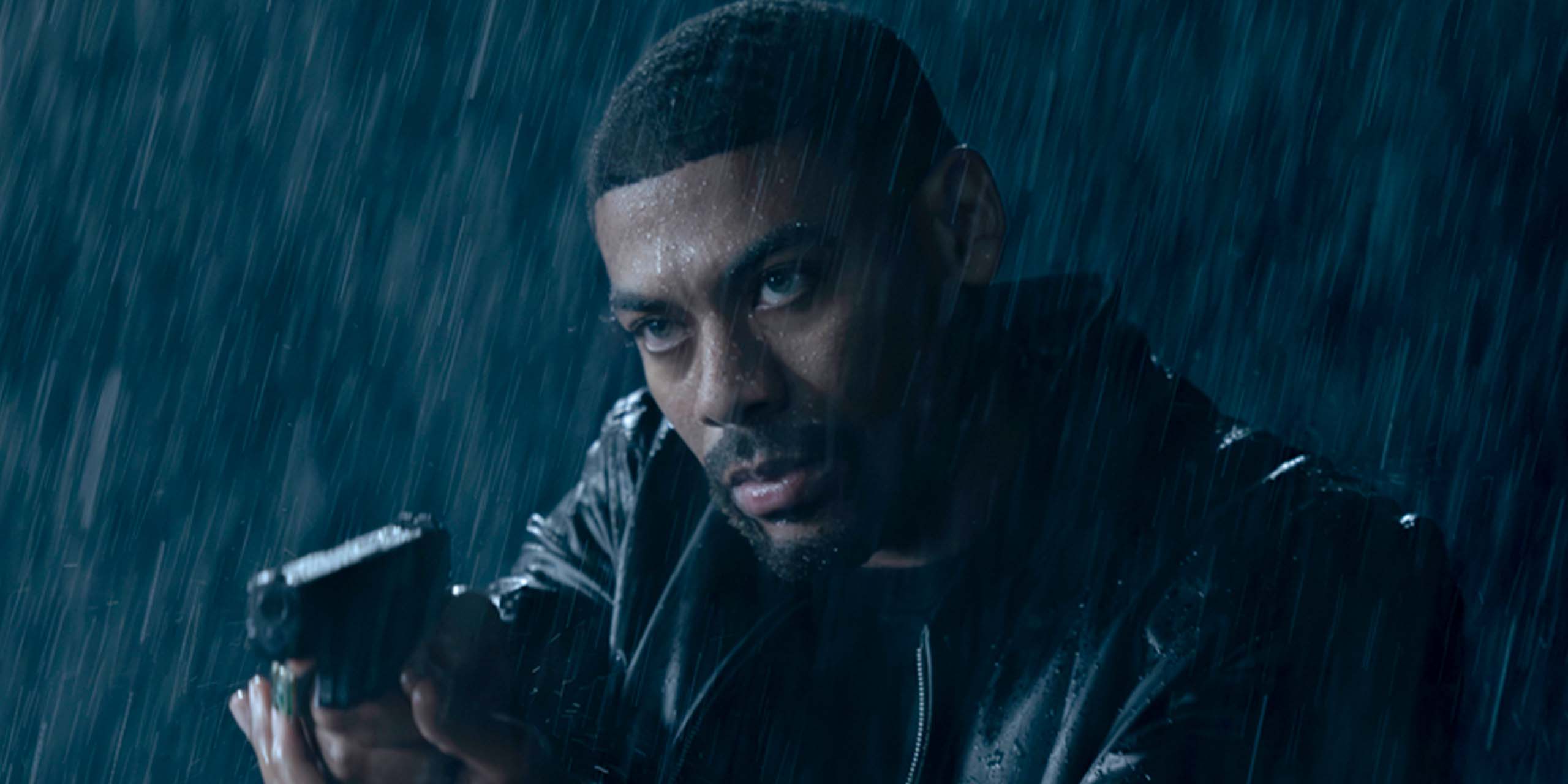 John Stewart (Aaron Pierre) pointant son arme, sous la pluie, dans Lanterns.