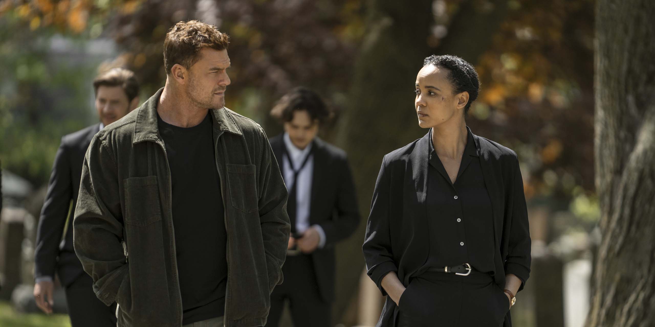 Jack Reacher (Alan Ritchson) et Frances Neagley (Maria Sten) marchant ensemble après la cérémonie d'un enterrement dans Neagley.