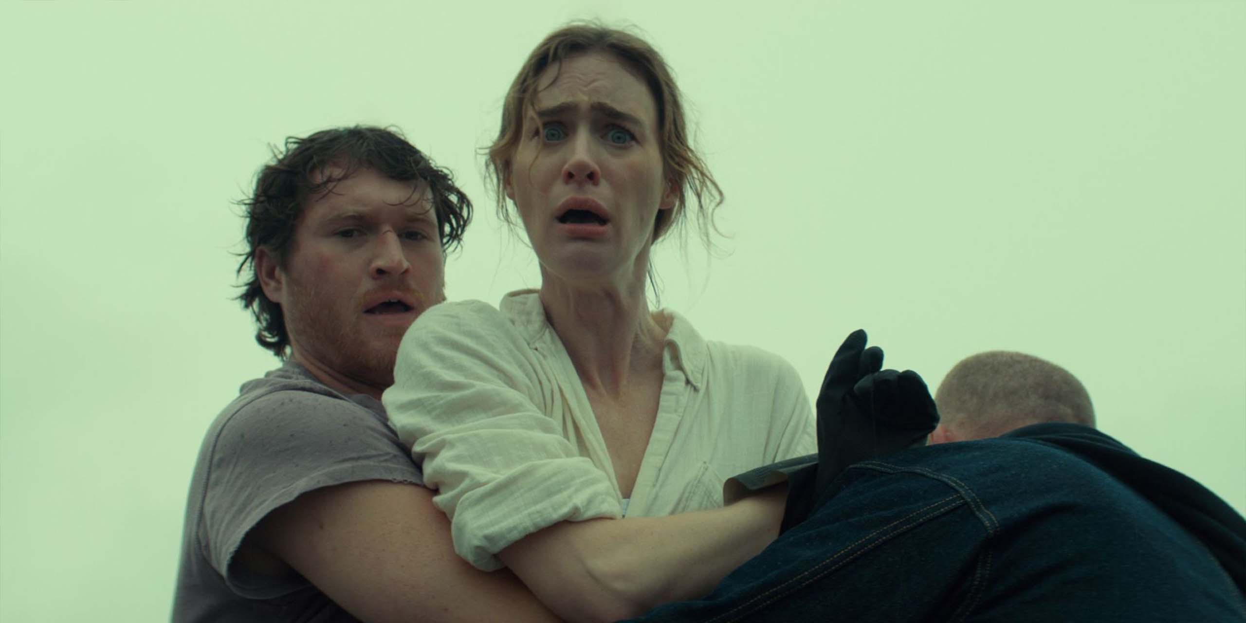 Mackenzie Davis, bouleversée et retenue par deux hommes, apparaît dans la série Below de Netflix.