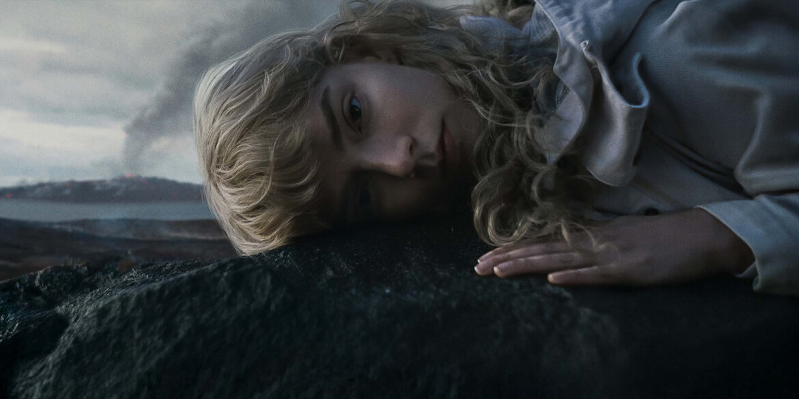 Joan (Anya Taylor-Joy), la tête posée sur un rocher volcanique, dans Sacrifice.