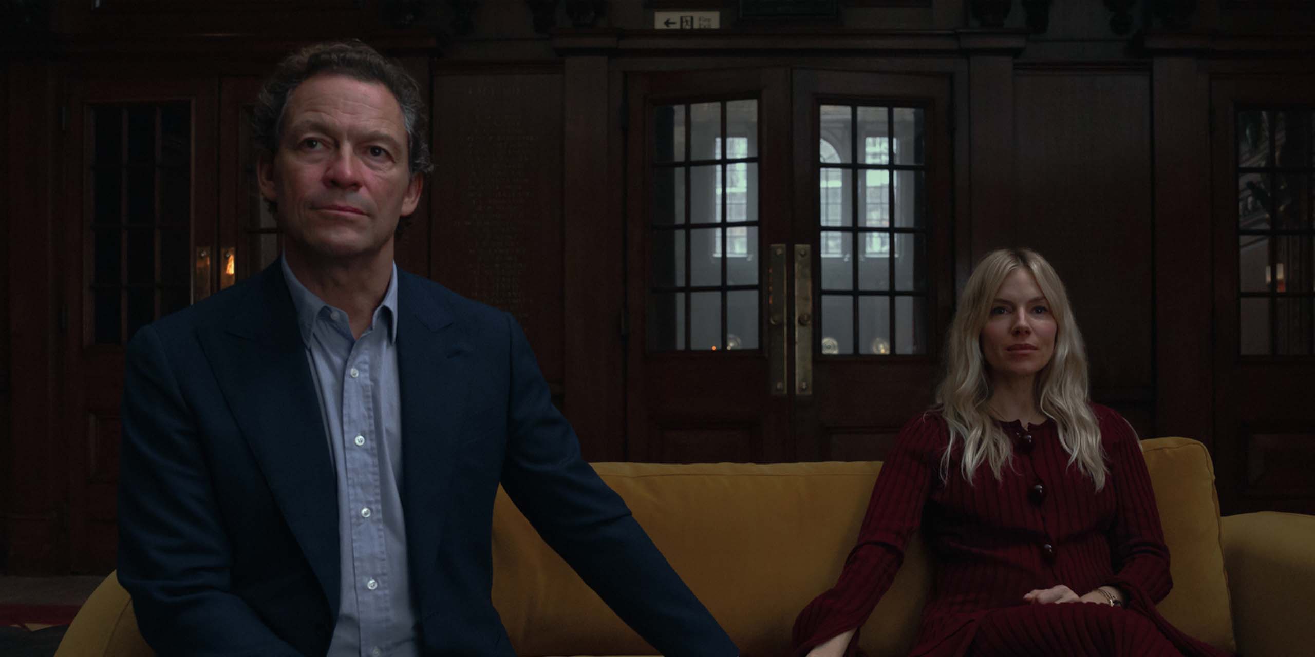 Morgan Henderson (Dominic West) et Carla Duval (Sienna Miller) se tenant la main sur un canapé dans la saison 1 de War.